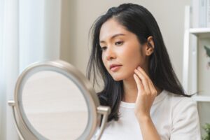 Woman looking in the mirror at her clear skin from acne treatment in Leesburg, FL